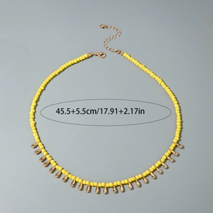 Détail du collier de perles jaunes avec breloques goutte dorées et longueur ajustable