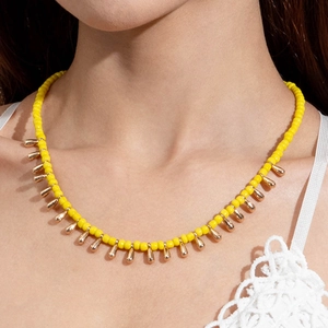 Détail du collier de perles jaunes avec pendentifs gouttes d'or sur dentelle