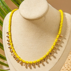 Détail du collier bohème en perles jaunes avec pendentifs gouttes dorées sur mannequin