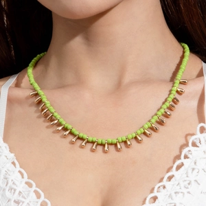 Détail du collier bohème en perles vertes avec pendentifs dorés en forme de goutte
