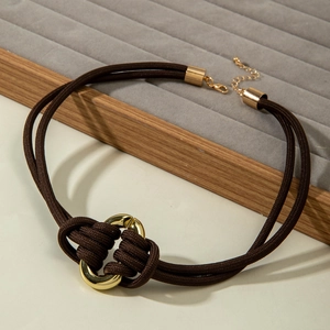 Détail d'un collier en cordon tressé marron avec nœud en anneau doré et fermoir réglable
