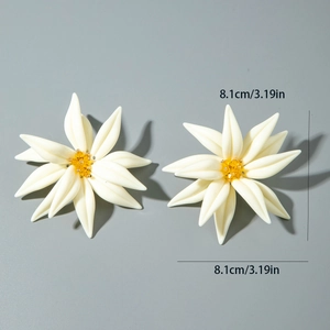 Détail de grandes boucles d'oreilles fleurs en résine blanche avec pistils dorés et 8,1 cm
