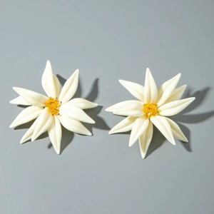 Vue détaillée de boucles d'oreilles fleurs en résine blanche avec perles jaunes au centre