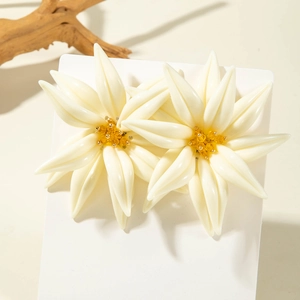 Détail de grandes boucles d'oreilles fleurs en résine blanche avec cœurs perlés