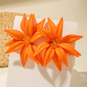Gros plan de boucles d'oreilles fleurs en résine orange avec perles jaunes au centre