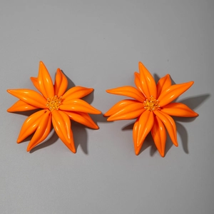 Détail de grandes boucles d'oreilles fleurs en résine orange avec perles jaunes centrales