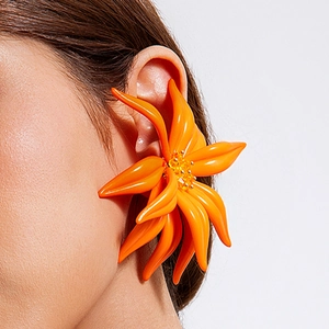 Gros plan d'un ear cuff floral surdimensionné en résine orange vif au fini brillant