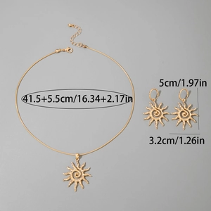 Détail d'une parure dorée motif soleil avec pendentif spirale et boucles d'oreilles
