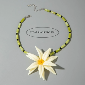 Détail d'un collier en perles de marbre vert avec un grand pendentif fleur en résine blanche