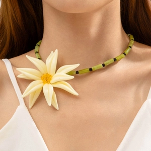 Vue détaillée du pendentif fleur en résine beige sur un collier de perles vertes