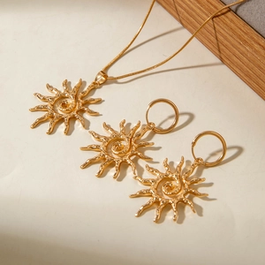 Vue macro de l'ensemble pendentif soleil et boucles d'oreilles dorés avec texture