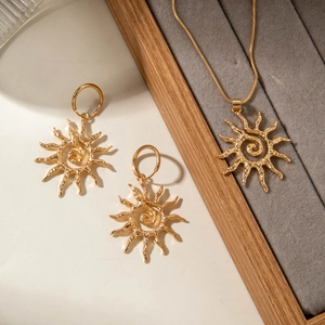 Vue détaillée du collier soleil doré et des créoles avec texture à rayons en spirale