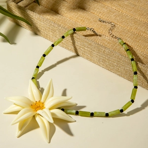 Détail d'un collier de perles avec grande fleur en résine blanche et perles vertes cylindriques
