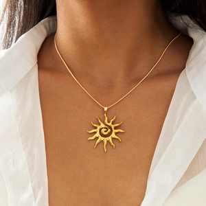 Détail d'un pendentif soleil doré vintage avec centre en spirale et texture martelée