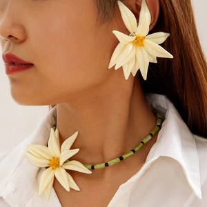 Détail du modèle portant des boucles d'oreilles fleur en résine et un collier de perles
