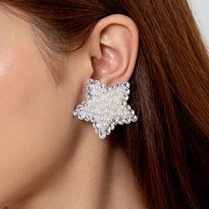 Boucles d'oreilles étoile avec perles et strass portées sur l'oreille du modèle