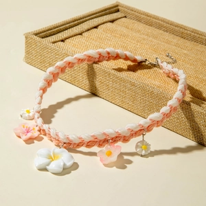 Detail of pink and white woven necklace with floral pendants on linen display tray