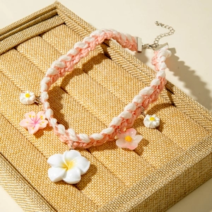 Detail of pink and white woven necklace with resin daisy and frangipani flower charms