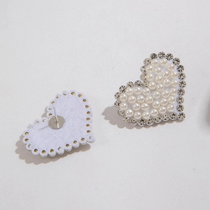 Détail macro de boucles d'oreilles en forme de cœur avec perles d'imitation et strass brillants