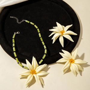 Détail d'une parure de bijoux à fleurs avec fleurs en résine blanche et perles vertes