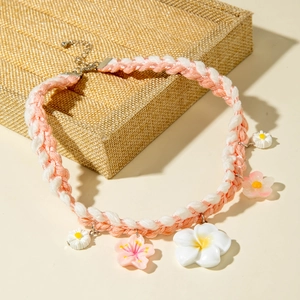 Detail view of pink and white woven necklace featuring floral charms and metal clasp