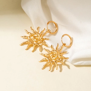 Gros plan de boucles d'oreilles soleil dorées avec spirale et fini martelé sur soie