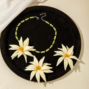Détail d'un collier bohème en perles de jade vert avec des accents de fleurs en résine