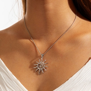 Détail du collier pendentif soleil argenté avec motif en spirale et texture martelée