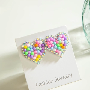 Gros plan de boucles d'oreilles cœur aux couleurs macaron avec strass sur carte
