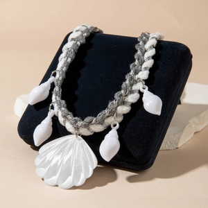 Detail of woven rope necklace with five white resin shell pendants on jewelry display