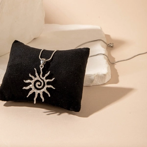 Détail macro du pendentif soleil argenté avec texture spirale et finition martelée