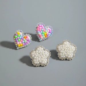 Détails de boucles d'oreilles cœur et fleur avec perles et strass sur fond gris