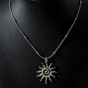 Détail du pendentif soleil argenté avec spirale centrale et chaîne à billes raffinée