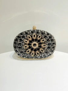 Close-up of luxury oval evening clutch featuring black floral crystals and diamond details