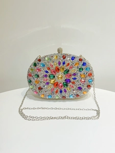 Close-up of luxury evening clutch with colorful rhinestones and silver chain strap