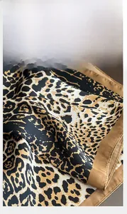 Detailed view of leopard print silk scarf with precision stitching and satin finish