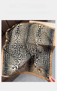 Detailed view of the leopard print silk-like scarf texture and brown satin hem edge