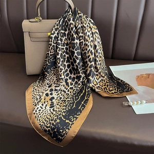 Classic leopard print silk scarf draped over a leather bag for elegant beach vacations