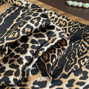 Detail of leopard print silk scarf with satin finish and elegant pearl accessory
