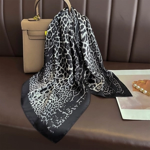Classic black and white leopard print silk scarf draped over a luxury handbag and sofa
