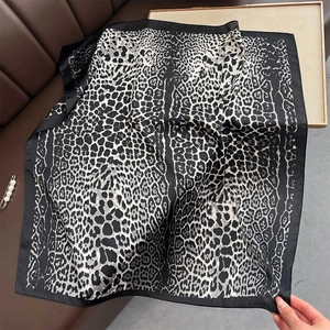 Close-up of leopard print silk scarf with black border on brown leather surface