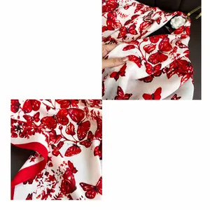 Dettaglio di sciarpa in seta con stampe di farfalle rosse e rifiniture di cucitura a macchina