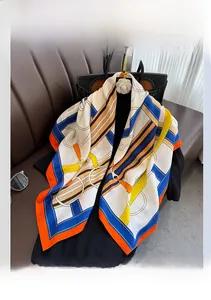 Detail view of equestrian buckle print scarf draped over a black luxury handbag on sofa