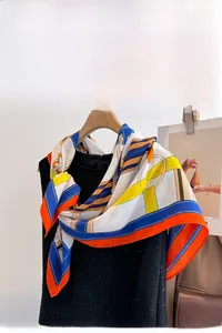 Detail of vibrant geometric silk scarf in orange and blue with anti-wrinkle satin texture