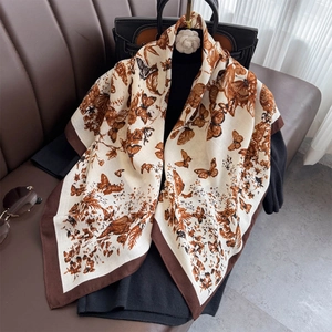Dettaglio di un elegante foulard di seta con stampa di farfalle e fiori su sfondo scuro