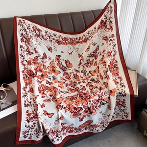 Dettaglio di un foulard quadrato con stampa a farfalla su divano in pelle