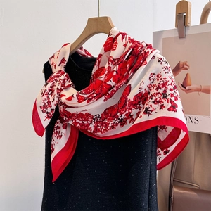 Dettaglio foulard in seta con fiori rossi e farfalle abbinato a un abito nero