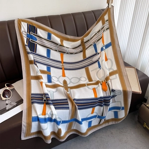 Detail of silk scarf with equestrian belt print draped over a brown leather sofa