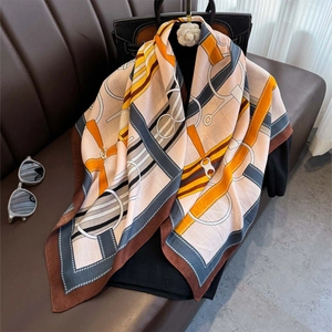 Silk scarf with luxury orange and brown belt prints draped over a black handbag