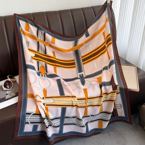 Close-up of silk scarf with equestrian belt print draped over a brown leather sofa
